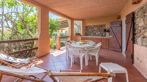 A covered outdoor area with a dining table, chairs, and a small stool. - Erica Piano Terra 150m From the Beach, Golfo Aranci, Italy (Golfo Aranci)