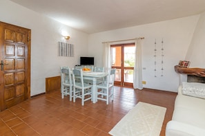 Un comedor con una mesa y sillas, un televisor y una puerta de madera.