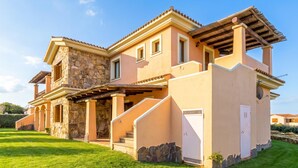 Une maison à deux étages avec une façade en pierre, un patio couvert et une pelouse bien entretenue.