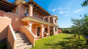 A two-story house with a balcony, a staircase, and a well-maintained lawn. - Le Dimore di Nettuno 2 With Pool, Pittulongu, Italy (Pittulongu)
