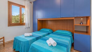A room with two beds, a window, and a blue wardrobe. - Le Dimore di Nettuno 2 With Pool, Pittulongu, Italy (Pittulongu)