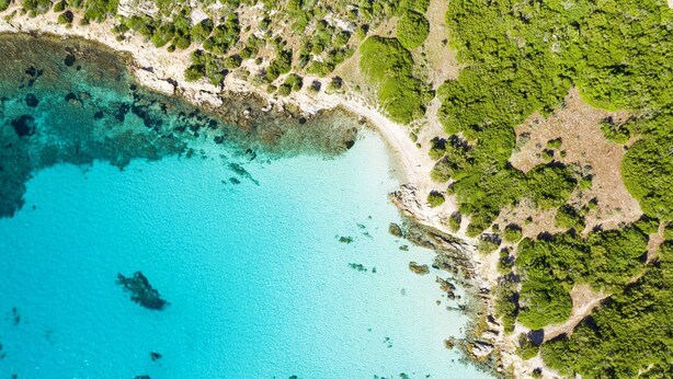 Vue aérienne d’une zone côtière avec des eaux turquoise limpides, des plages de sable et une végétation luxuriante.