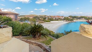Une vue sur la côte, avec une plage de sable, un ciel bleu dégagé et un mélange de bâtiments résidentiels.
