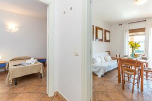 Habitación de hotel con cama, escritorio con silla, ventana con cortinas y lámpara de pared.