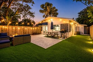 A backyard with a barbecue area, a fire pit, and outdoor furniture.