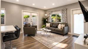 A modern living room with a sofa, coffee table, and a dining area with a table and chairs. - Poinsettia Paradise - 2 BDR Wing Near Beach (Fort Lauderdale)