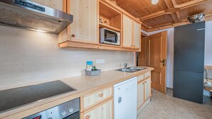 Een moderne keuken met houten kastjes, een ingebouwde magnetron, een roestvrijstalen spoelbak en een vaatwasser.