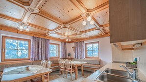 Een knus houten interieur met een eethoek, bankjes en een keuken met een spoelbak.