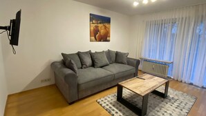 A living room with a grey sofa, a wooden coffee table, and a patterned rug. - Vacation apartment Leo, 65 sqm 1st floor, 2 bedrooms (Bad Endorf)