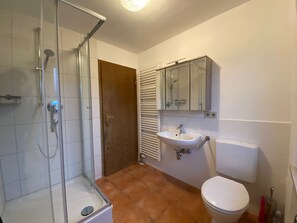 Ein Badezimmer mit Duschkabine, Waschbecken und Toilette.