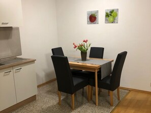 Eine kompakte Küche mit eingebautem Herd, einem Esstisch mit vier Stühlen und einem kleinen Topfpflanzen auf dem Tisch.