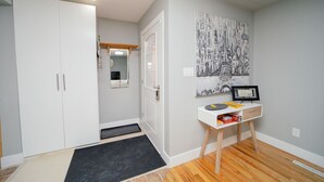 A hallway with a white wardrobe, a door leading to another room, a small desk with a mirror, and a framed picture on the wall. - Cozy 3 Bedroom Contemporary Home With Free Parking  (Edmonton)