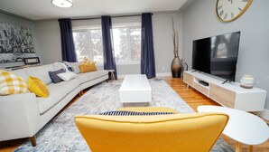 A modern living room with a sofa, coffee table, and a TV. - Cozy 3 Bedroom Contemporary Home With Free Parking  (Edmonton)