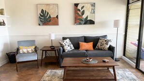 A living room with a grey sofa, a wooden coffee table, a grey armchair, and two wall-mounted paintings.