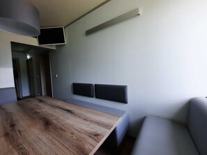Una habitación moderna con una mesa de madera, un sofá gris y un televisor de pantalla plana en la pared.