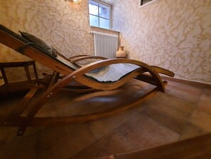 Una mecedora de madera en una habitación con paredes de piedra y un radiador.