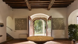 Una habitación con una mesa de madera, una escalera y dos grandes mapas murales.