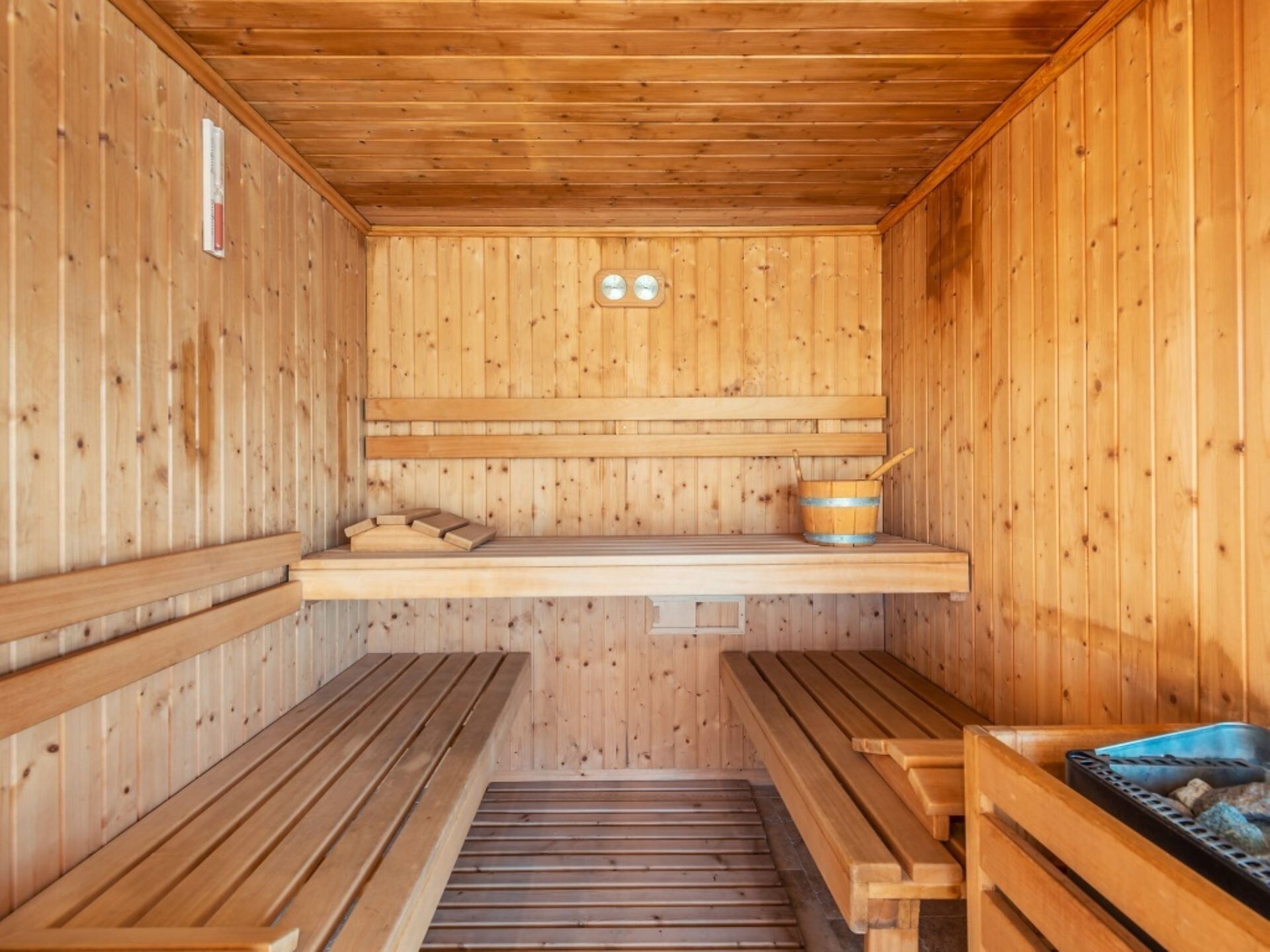 A sauna with wooden benches, a bench seat, a wooden wall, and a wooden ceiling.