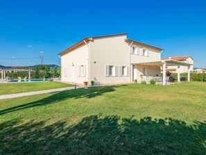 Una casa a due piani con piscina, patio coperto e prato curato.