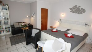 Una habitació d'hotel moderna amb un llit, un sofà, una cadira, una taula petita i una biblioteca.