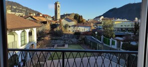 A balcony with a view of a town, including a tower and various buildings.