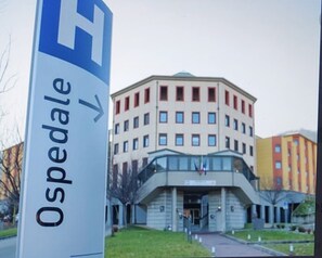 A building with a sign indicating 'Ospedale' and a directional arrow.