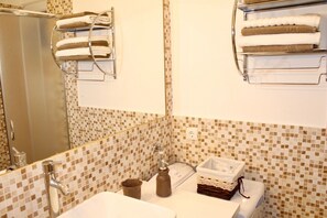 Ein Badezimmer mit gefliestem Mosaik-Spritzschutz, einem Waschbecken, einem Spiegel und Handtuchhaltern.