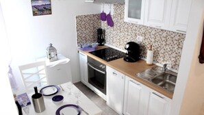 A compact kitchen with white cabinets, a wooden countertop, a stove, an oven, and a sink. - Studio apartment Miko - top location, great place to enjoy (Split)