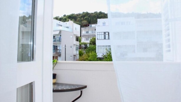A balcony with a table and chairs, overlooking a residential area with modern buildings and a hill in the background. - Studio apartment Miko - top location, great place to enjoy (Split)