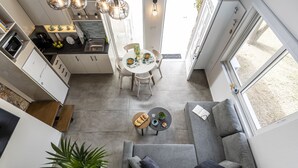 A modern kitchen with a dining area, a gray sofa, and a large window. - EPTA Houses (KOS)