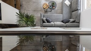 A modern living room with a grey sofa, a coffee table, and a potted plant. - EPTA Houses (KOS)