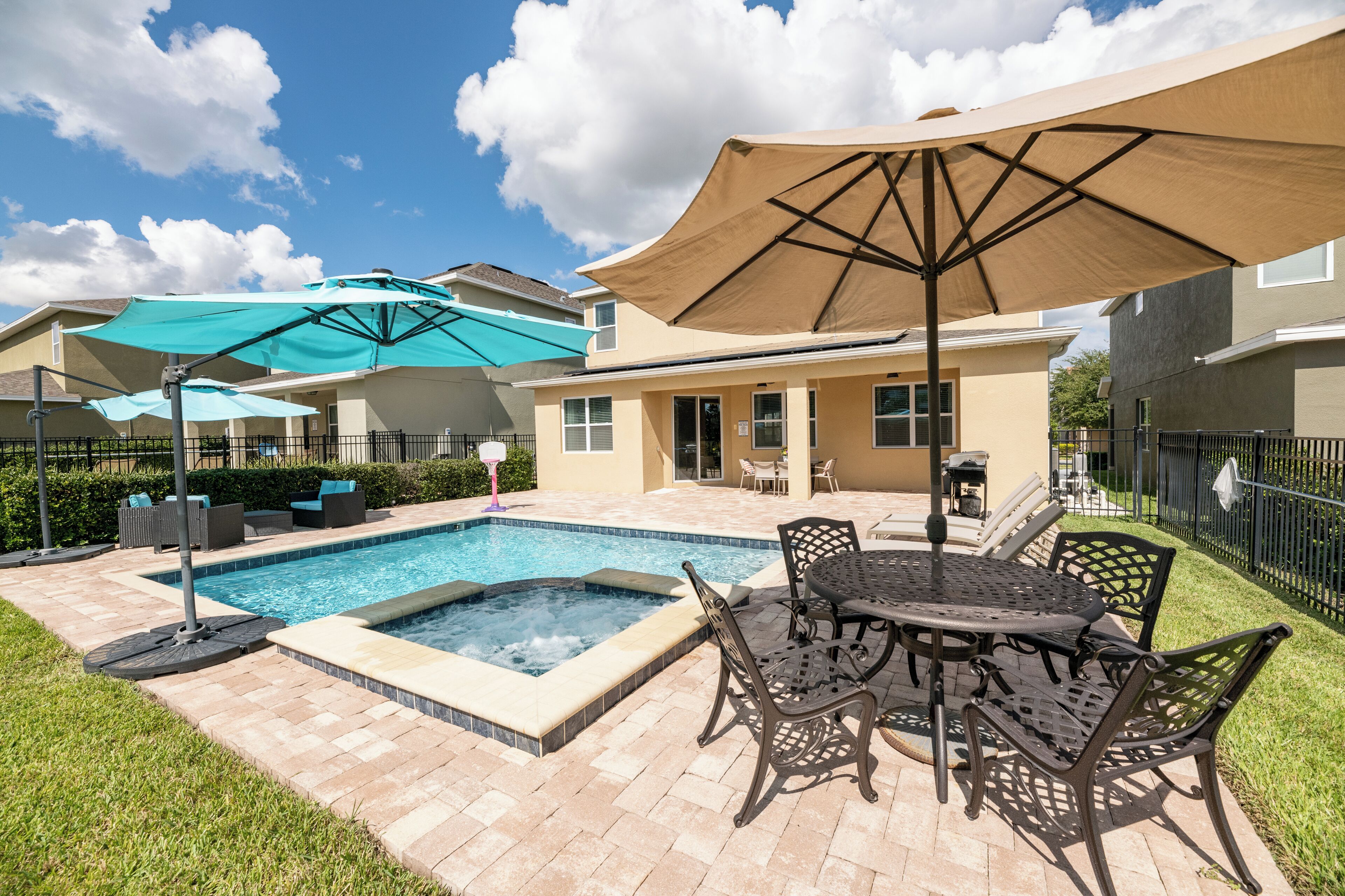 A backyard with a swimming pool, patio furniture, and umbrellas.