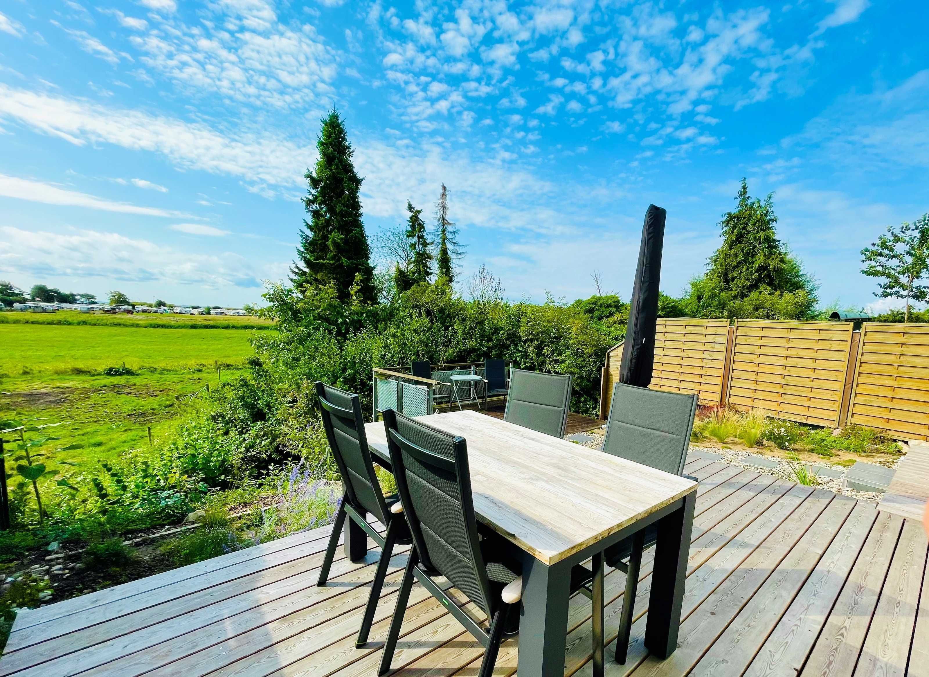 An outdoor patio with a wooden deck, a table, and chairs.