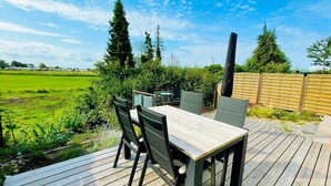 Une terrasse extérieure avec une plateforme en bois, une table et des chaises.