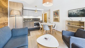 Un salon moderne comprenant un coin repas, une cuisine et un téléviseur fixé au mur.