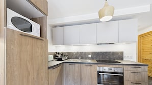 Une cuisine moderne avec des meubles en bois, un four encastré et un four à micro-ondes.