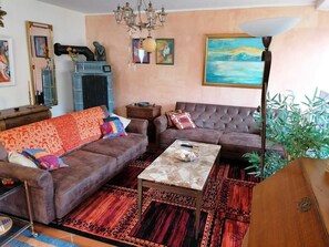 A living room with two sofas, a coffee table, a chandelier, and a painting on the wall. - Constance mountain view with winter garden (Oberstaufen)