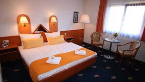 A hotel room with a large bed, two bedside tables, a desk with a chair, a window with curtains, and wall-mounted lamps. - Apartment handicapped accessible (balcony or terrace) - Hanse-Kogge Hotel & (Koserow)