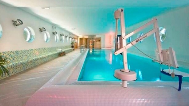A swimming pool with a water slide and a changing room area with mirrors and a tiled wall. - Apartment handicapped accessible (balcony or terrace) - Hanse-Kogge Hotel & (Koserow)
