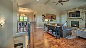 A spacious living room with a fireplace, leather sofa, and a stone accent wall. - Luxe Canyon Lake Home w/ Gorgeous Lake Views! (Canyon Lake)
