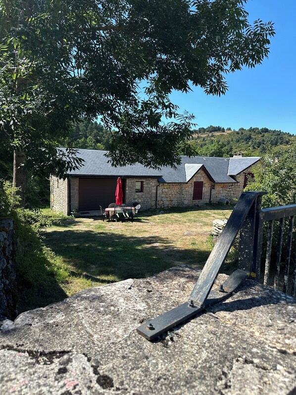 Un edificio de piedra con un porche cubierto, una puerta roja y una mesa con sillas.