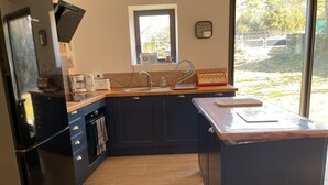 Una cocina con horno integrado, un lavamanos y una ventana con vistas a un jardín.