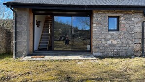 Un edificio moderno de piedra con un amplio ventanal y una escalera de madera que conduce a la entrada.