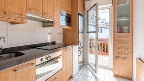 Eine moderne Küche mit Holzausstattung, Edelstahlgeräten und Blick auf den Balkon.