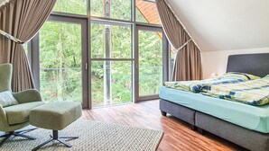 A bedroom with a large window, a bed, a chair, and a rug. - Cozy home in Lautenthal with sauna (Lautenthal)