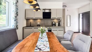 A modern kitchen with grey cabinets, a wooden dining table with a floral placemat, and a vase of flowers. - Cozy home in Lautenthal with sauna (Lautenthal)