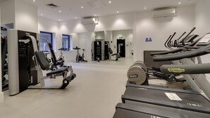 A modern gym with cardio equipment, weight machines, and a mirrored wall. - Apartment Sleeps 2 With Free Parking (Slough)