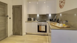 A modern kitchen with white cabinets, a microwave, a kettle, and a tray with breakfast items. - Apartment Sleeps 2 With Free Parking (Slough)