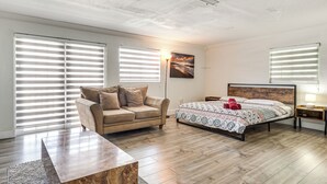 Un dormitorio con cama, sofá, mesita de noche y lámpara.