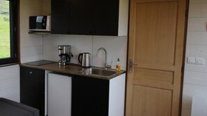 A compact kitchen with a microwave, coffee maker, sink, and a refrigerator. - Seljalandsfoss Cottage (Rangárþing eystra)